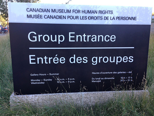 Black and white sign saying Group Entrance along with information about the Museum opening hours